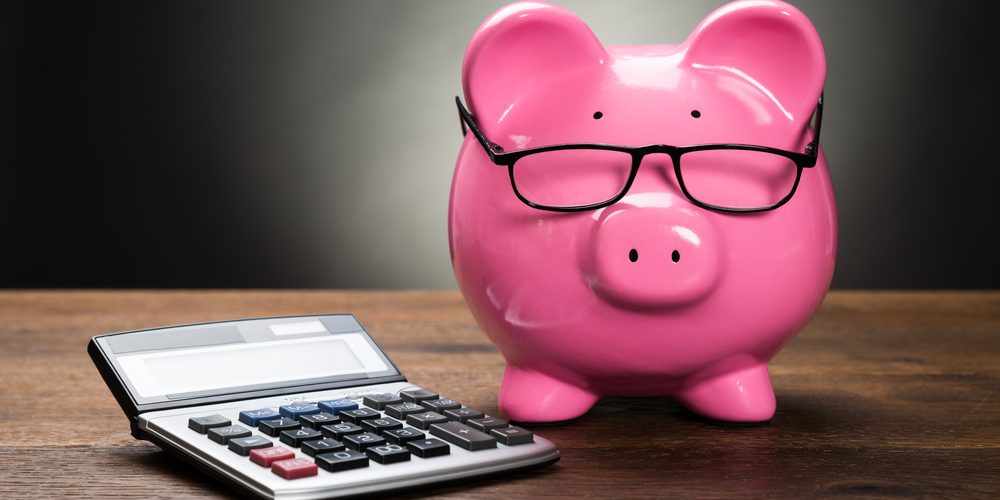 Pink,Piggybank,With,Calculator,On,Wooden,Table